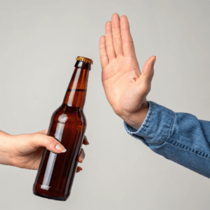 Une main rejetant une bouteille d'alcool, représentant la décision consciente de se libérer de la dépendance à l'alcool et de prendre un nouveau départ pour une vie plus saine, sans alcool